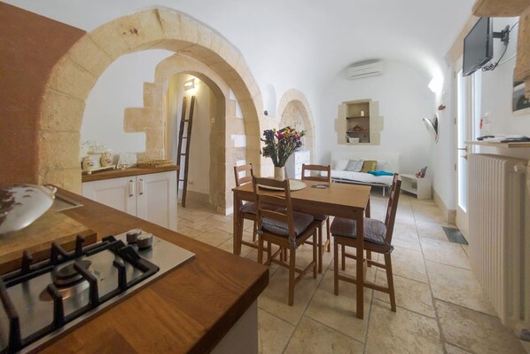 Una cocina compacta con estufa a gas, sillas de madera y una mesa de comedor.