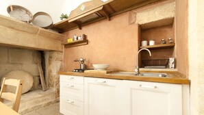 Una cocina pequeña con armarios blancos, encimera de madera y pared de piedra.