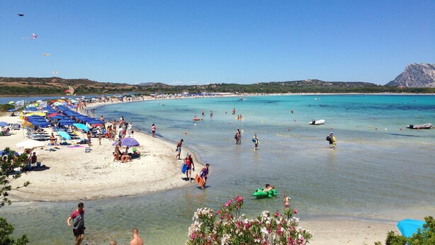 A beach with clear turquoise water, umbrellas, and people enjoying the seaside. - Terraced house with dehors adjacent beach in residence (San Teodoro)