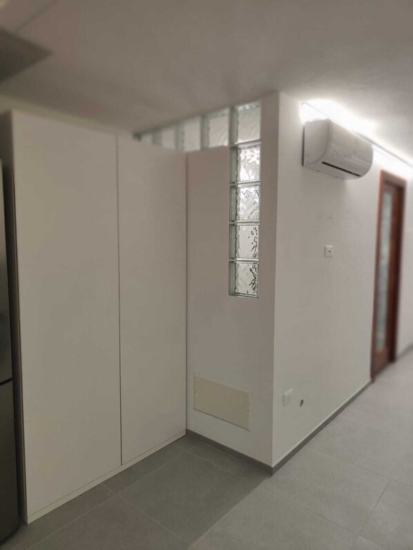 A modern room with a sliding door, a window with frosted glass, and an air conditioning unit mounted on the wall. - Terraced house with dehors adjacent beach in residence (San Teodoro)