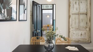 A dining area with a black table, wicker chairs, and a vase with green foliage. - Singular Stays Parque Central III (Valencia)
