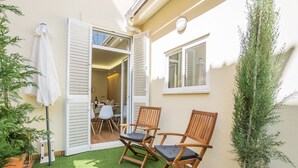 A patio with artificial grass, two wooden chairs, a potted plant, and a white umbrella. - The Dreams House with Green Patio (Lisboa)