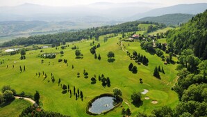 A golf course with a pond, trees, and a distant mountain range. - VILLA LIZ, private pool, private hot tub, park fenced,  close to Florence (Poppi)