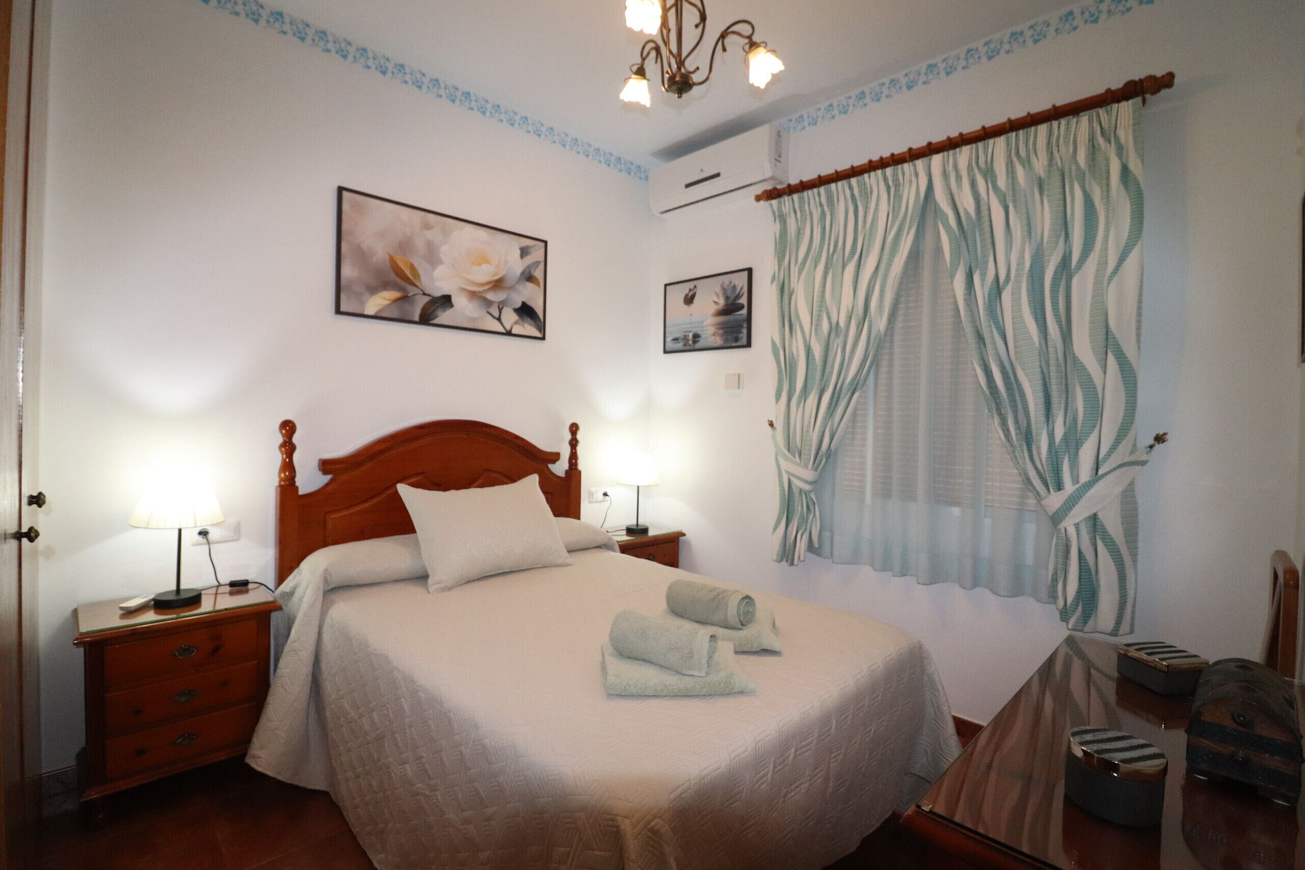 A neatly made bed with two towels, a wooden headboard, and a nightstand with a lamp.