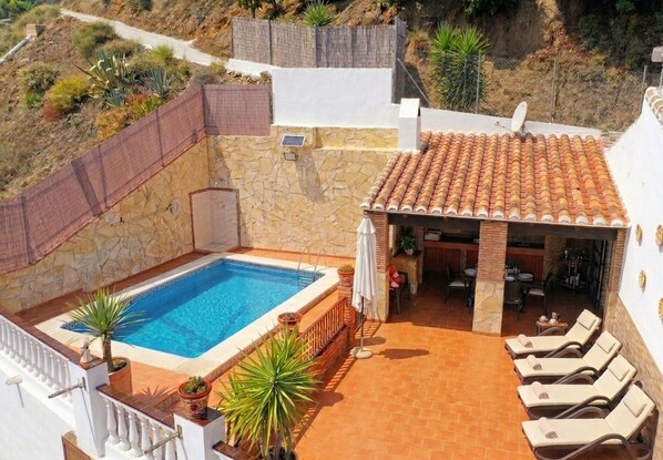 A rooftop pool with a stone wall, lounge chairs, and a bar area. - 1037 Villa Alabarce (Nerja)