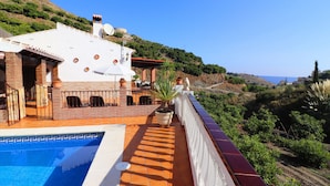 Une villa avec piscine, une terrasse agrémentée de plantes en pot et une vue sur la mer.