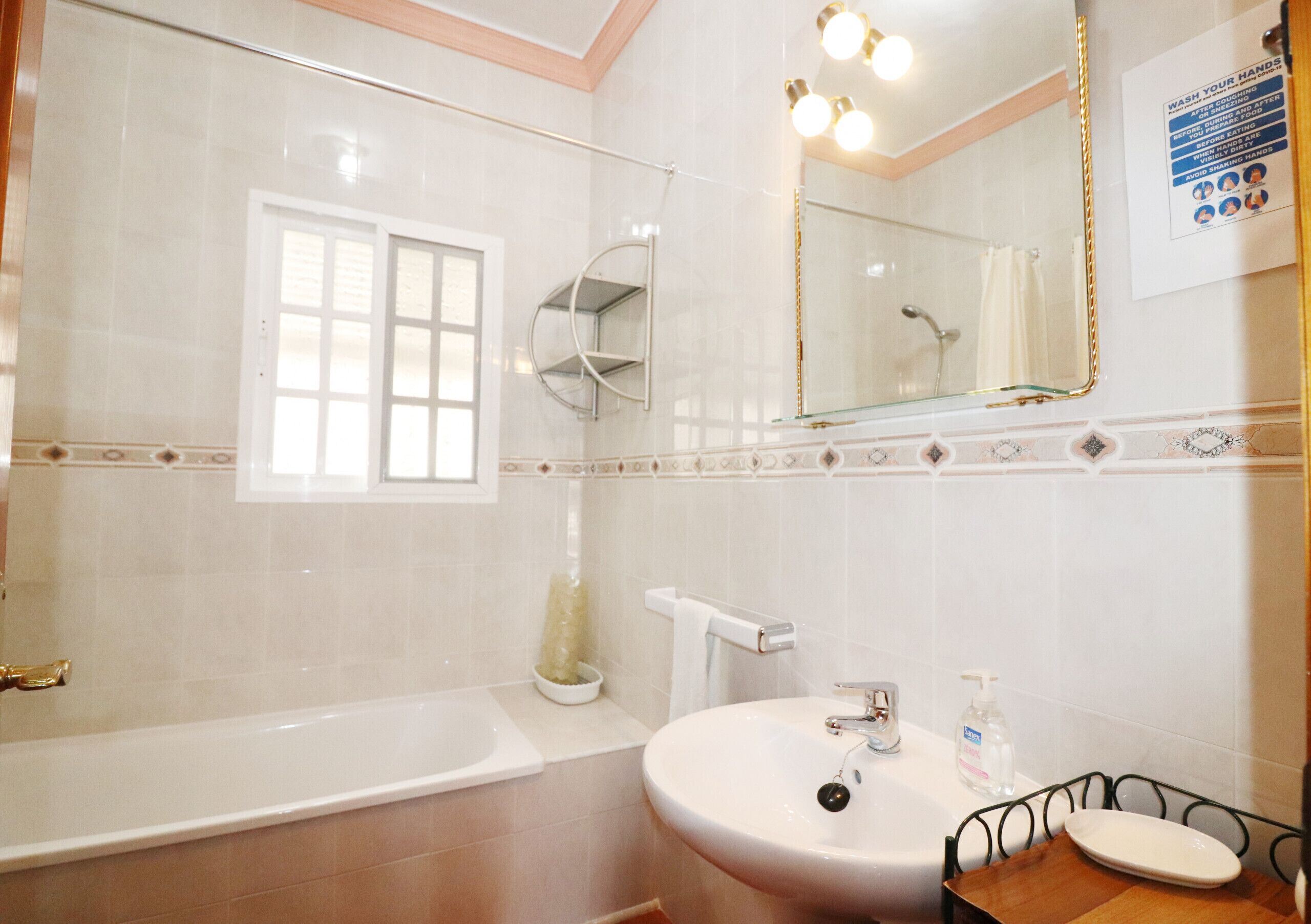 A bathroom with a bathtub, sink, and mirror.