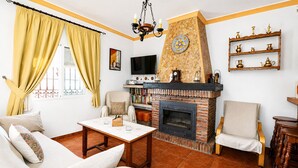 Un salon avec une cheminée, un canapé, un fauteuil et un téléviseur.