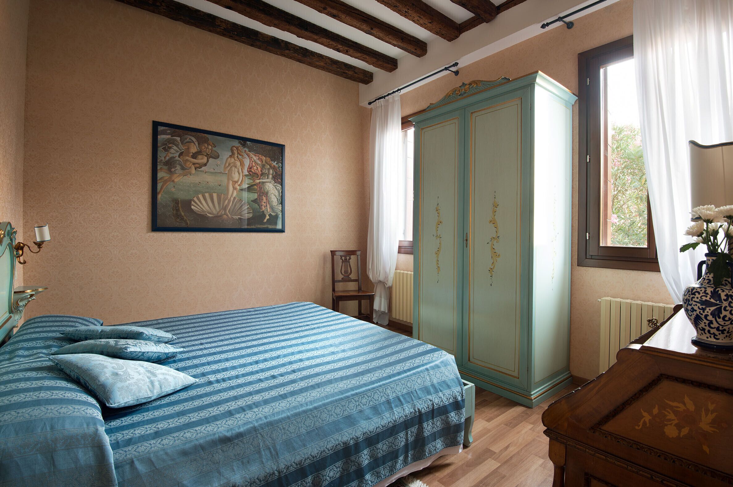 Une chambre à coucher avec un lit, une armoire, un tableau et une fenêtre avec des rideaux.