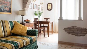 A cozy living room with a sofa, a dining table, and a kitchen area. - Elegant apartment with garden in S.Croce, Venice (Santa Croce)