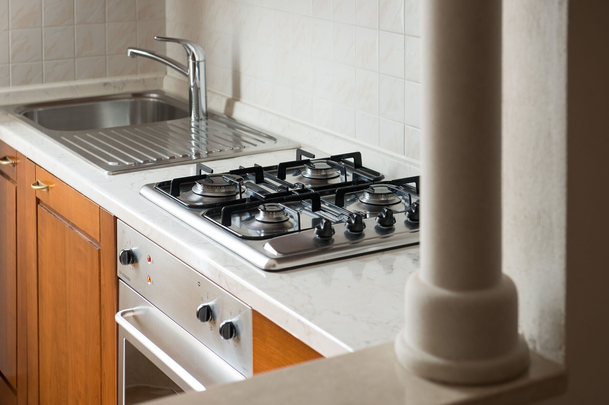 A kitchen with a stainless steel stove, a sink, and wooden cabinets.
