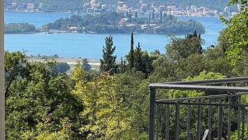 Une vue d’une ville côtière, avec des bâtiments le long du littoral, entourée de collines et d’arbres.