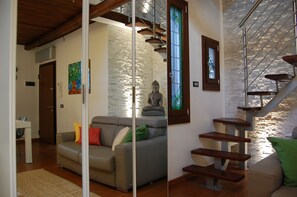 A modern living room with a sofa, a staircase, and a Buddha statue. - Loft with Terrace - Venice - Biennale (Venezia)
