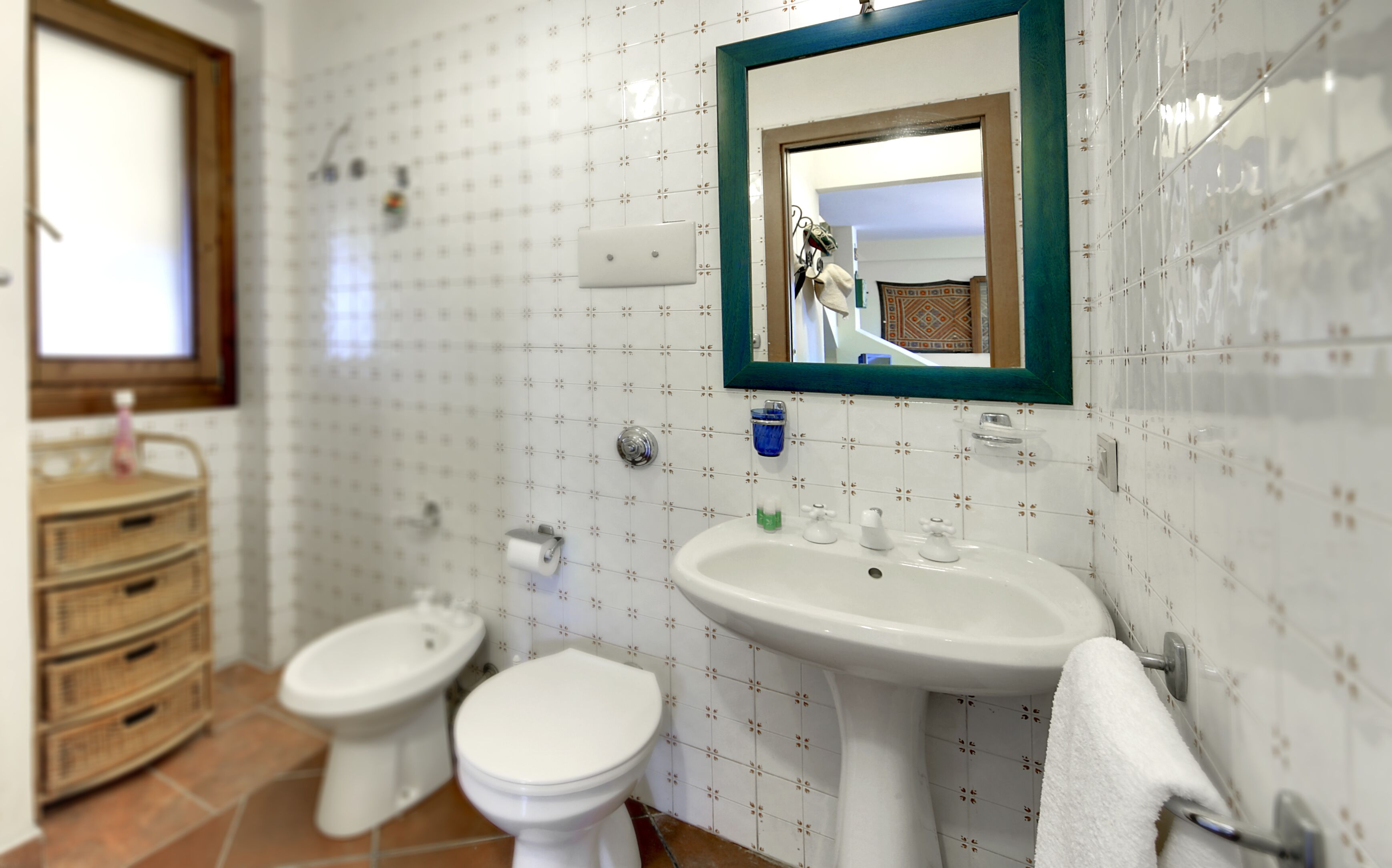 A bathroom with two toilets, a sink, and a mirror.