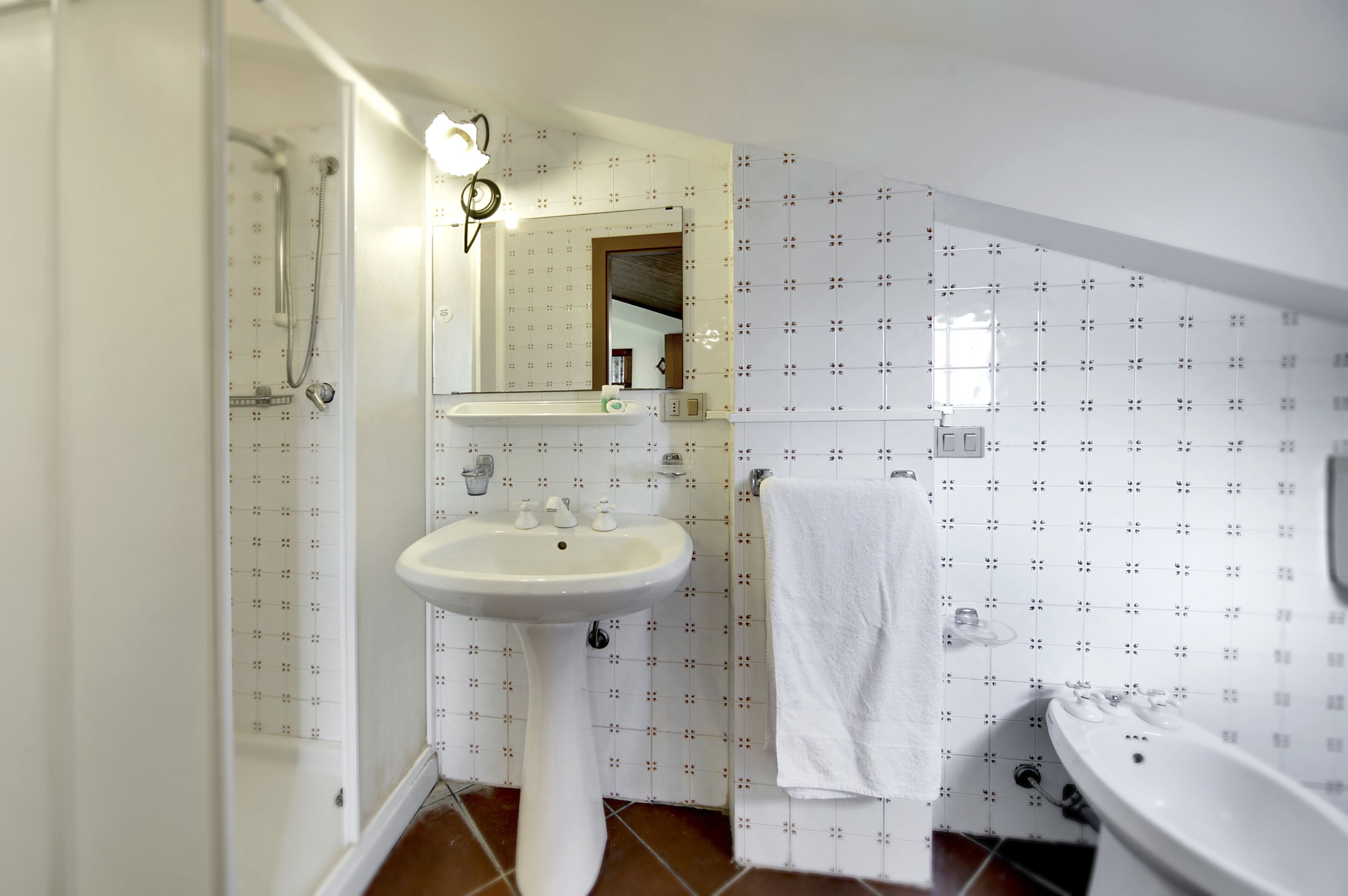 Un baño con lavamanos pedestal, espejo, ducha y bañera.