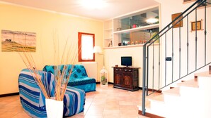 A living room with a sofa, a TV stand, and a staircase. - CASA GIULIA in BORSO DEL GRAPPA A holiday full of sport (Borso del Grappa)