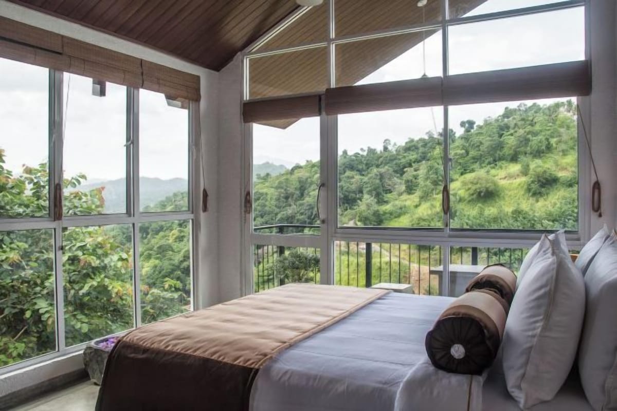 Un dormitorio con un ventanal grande con vistas a un paisaje verde y exuberante.