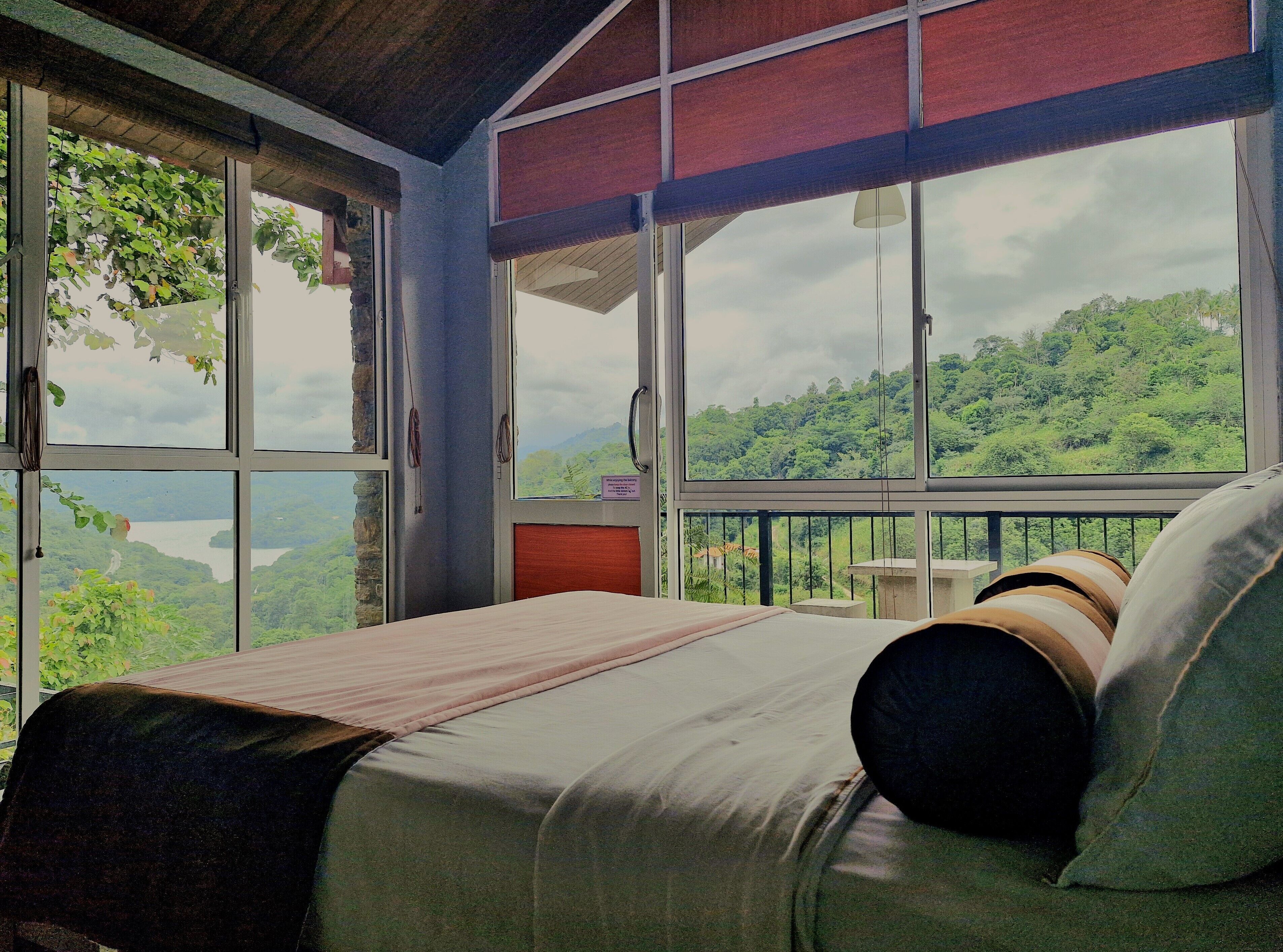 Un dormitorio con un ventanal que ofrece vistas a un paisaje verde y exuberante.