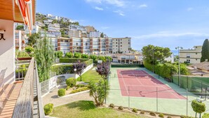 A residential building with a tennis court, a pool, and a garden area.