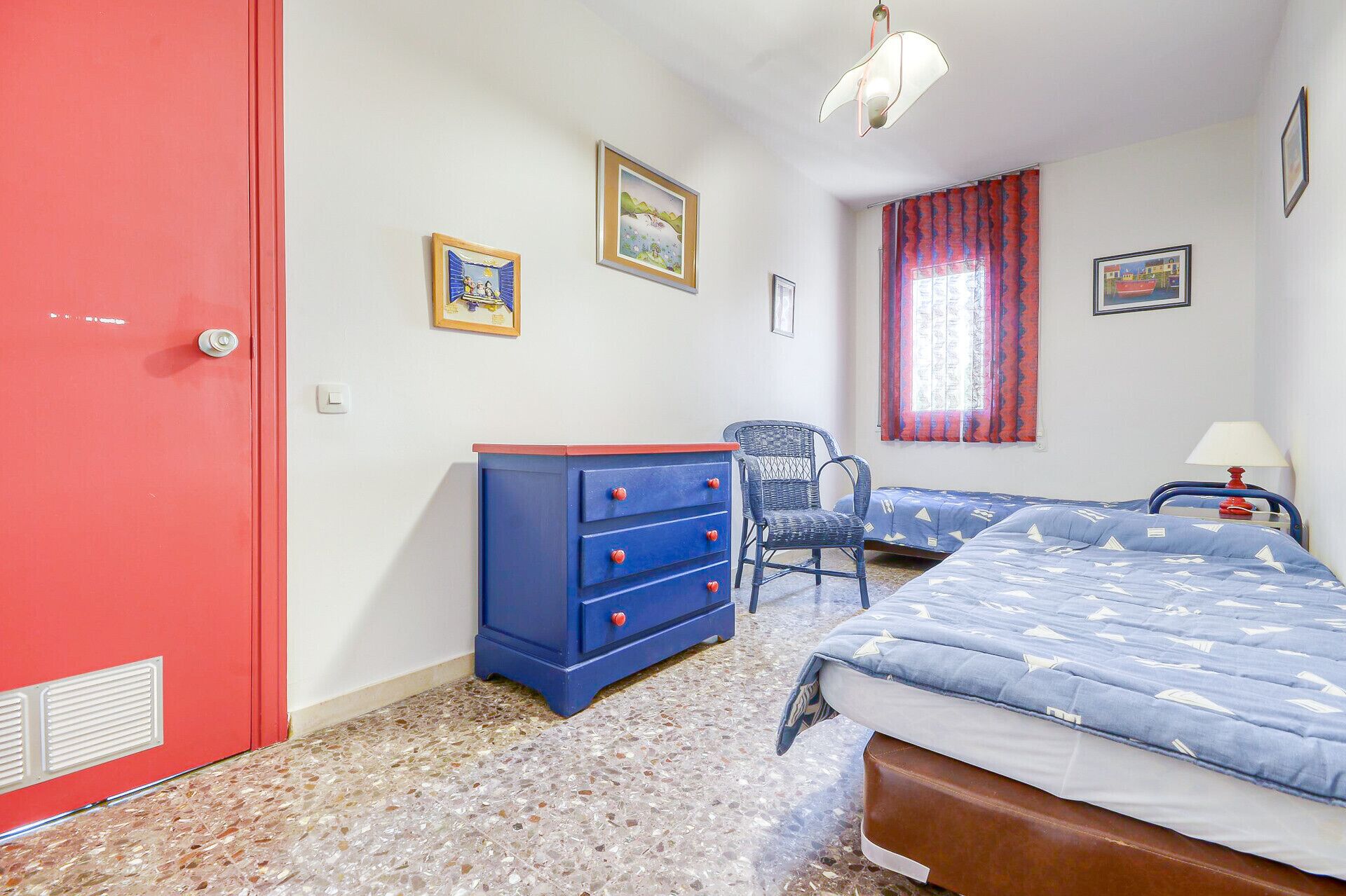 Een slaapkamer met een bed, een kaptafel, een stoel en een raam met gordijnen.