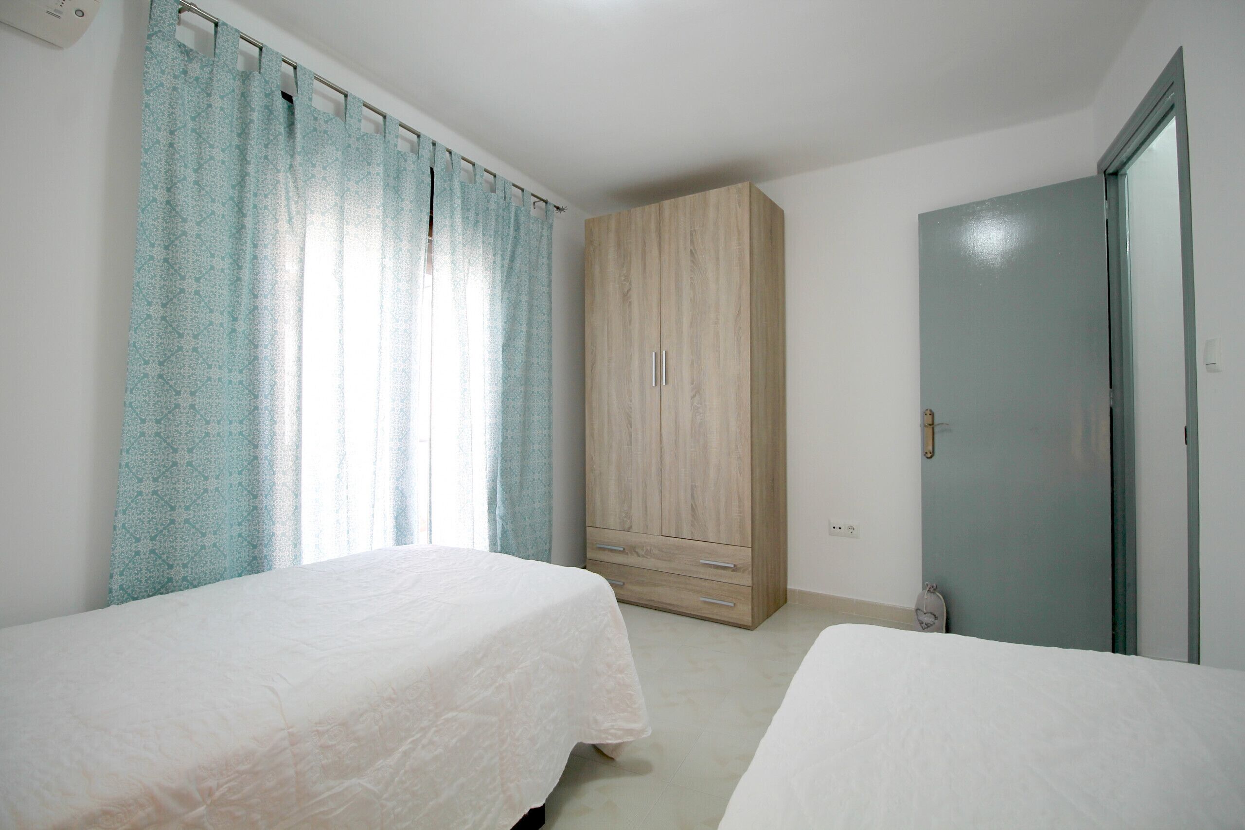 Un dormitorio con dos camas, un armario y una puerta.