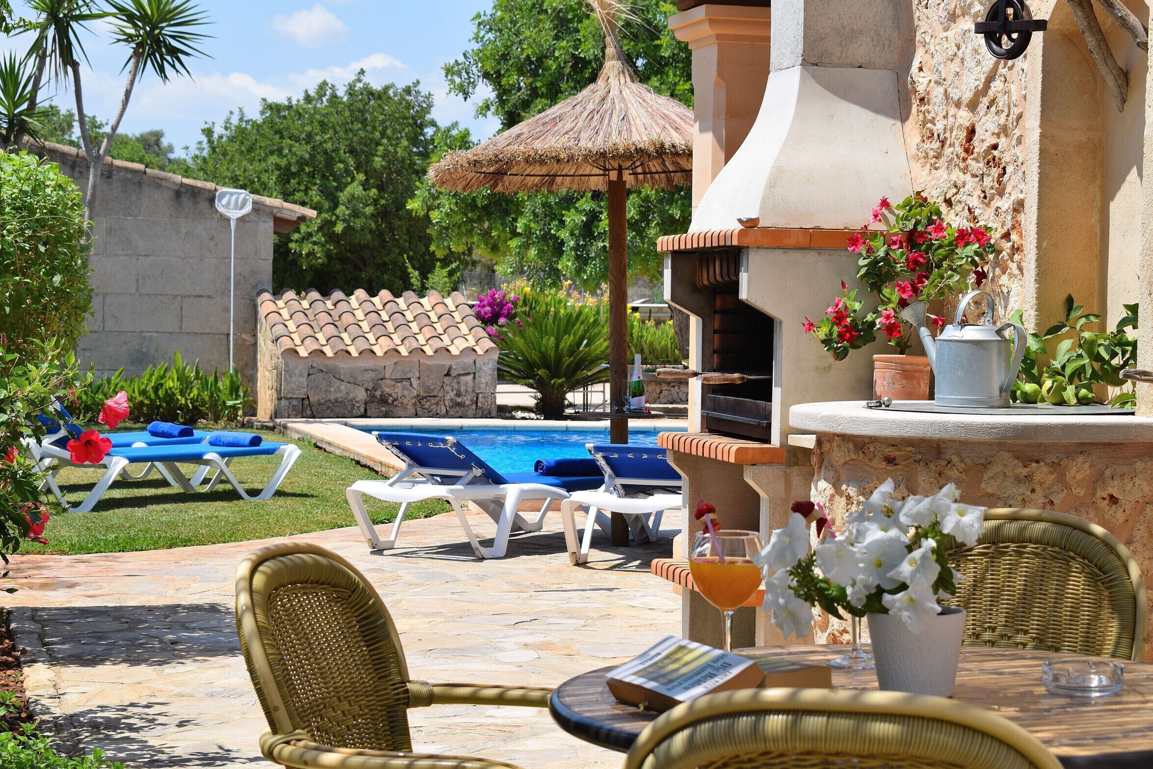A poolside area with lounge chairs, a barbecue grill, and a table with a drink.