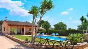 Ein Haus mit Swimmingpool, Fahrrad und Palmen.