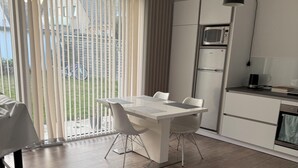 Una cocina moderna con comedor, que incluye una mesa y sillas blancas, un microondas y un refrigerador.