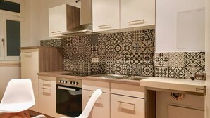 A kitchen with patterned tiles, a stove, and white cabinets.