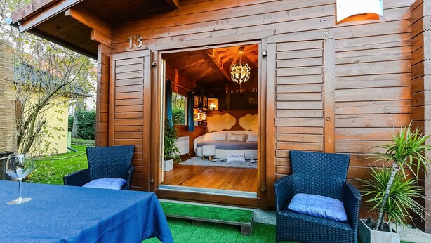 A wooden cabin with a cozy interior, a bed, a dining area with a table and chairs, and a small balcony with a potted plant. - House with garden in the center of Berlin for up to 3 people (Berlin)