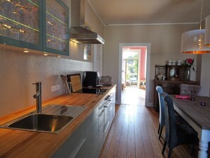 A modern kitchen with stainless steel appliances, wooden countertops, and a view to the dining area. - extravagant old building 80m² center, Lübeck, 3 bedrooms, kitchen, XXL sofa (St. Gertrud)
