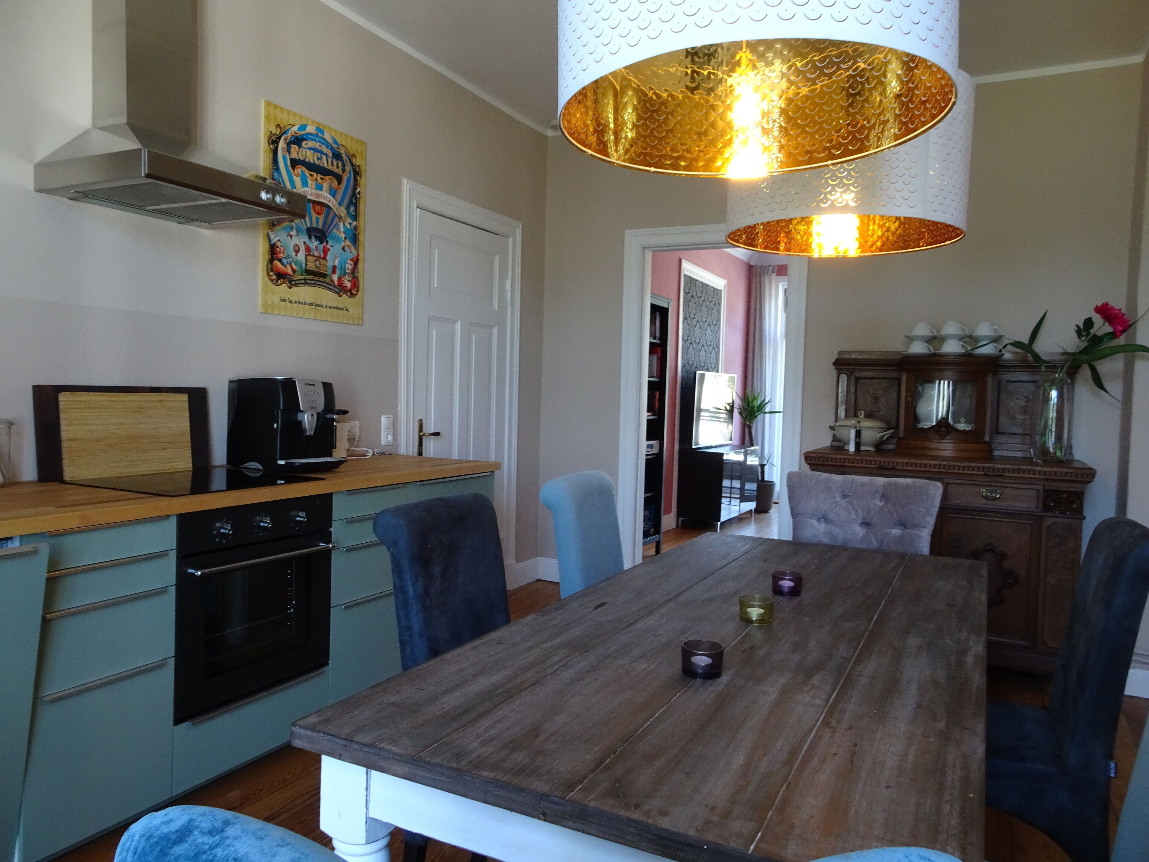 Een eetgedeelte met een houten tafel, stoelen en een hanglamp.
