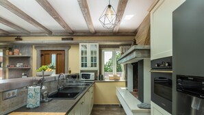 A modern kitchen with a central island, built-in appliances, and a stone fireplace. - Villa Loki- your exclusive Holiday Home in Istria (Lašići, Vizinada)
