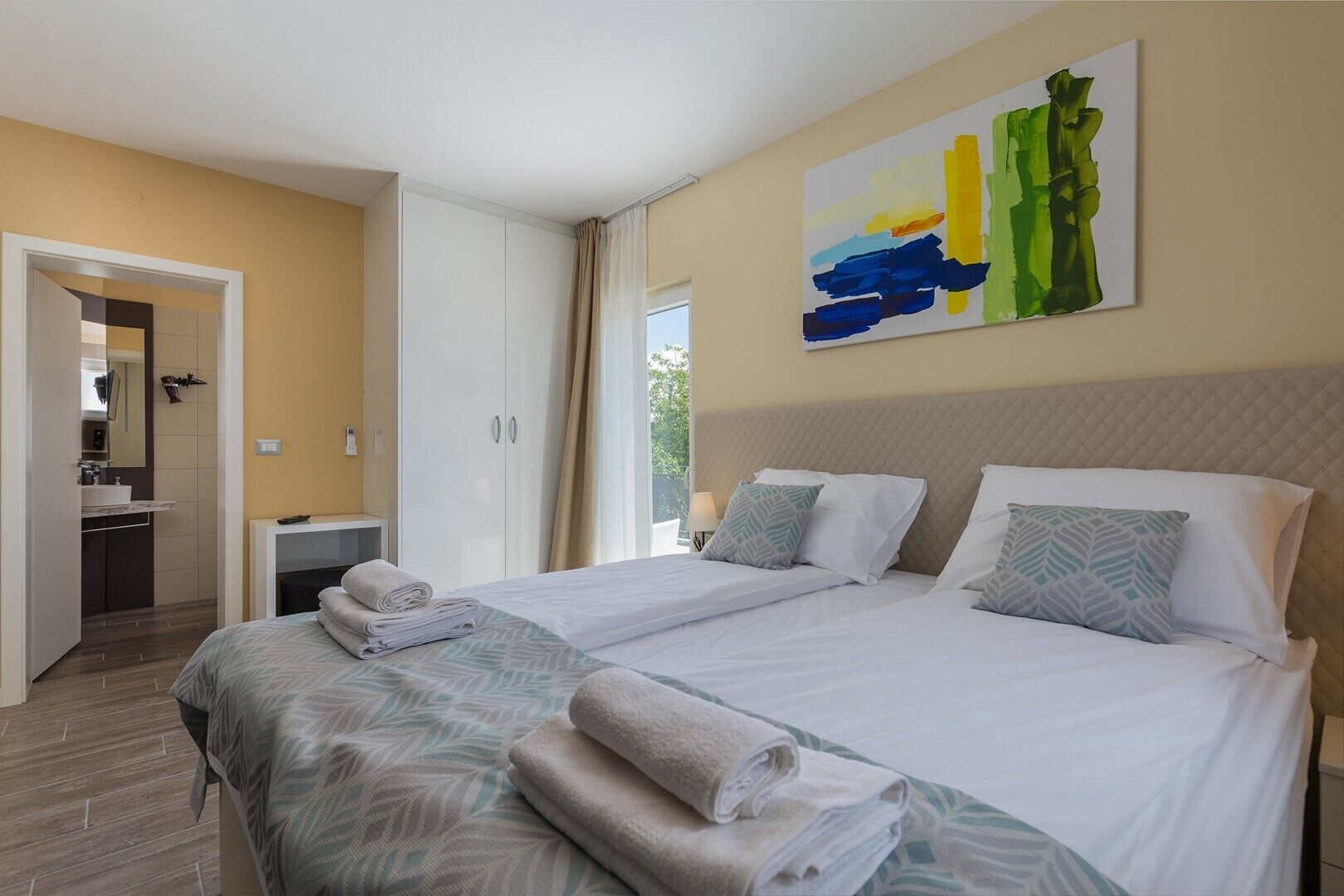 Une chambre d’hôtel avec deux lits, une salle de bain et un tableau au mur.