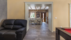 A living room with a black sofa, a dining area with a table and chairs, and a pool table. - Villa Loki- your exclusive Holiday Home in Istria (Lašići, Vizinada)