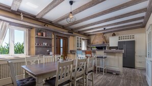 A spacious kitchen with wooden beams, a dining area with a table and chairs, and a view through a window. - Villa Loki- your exclusive Holiday Home in Istria (Lašići, Vizinada)