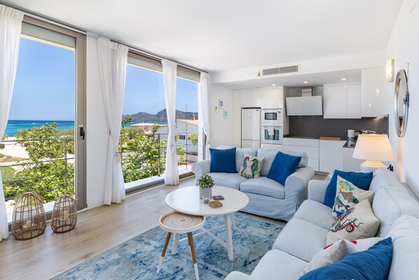 A modern living room with a sofa, a small table, and a view of the ocean.