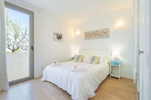 A bedroom with a bed, bedside tables, a window, and artwork on the walls.