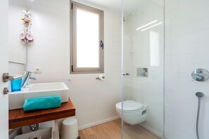 A modern bathroom with a glass shower enclosure, a white toilet, and a sink with a blue soap dispenser. - Sunny House With Sea Views in Son Serra, Mallorca (Son Serra de Marina)