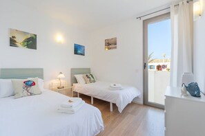 A hotel room with two beds, a window with a view, and artwork on the walls.