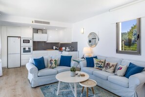 A modern living room with a sofa, a coffee table, and a kitchen in the background.