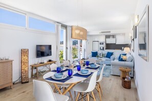 Ein modernes Wohnzimmer mit Essbereich, einer Küche und einem Fernseher.