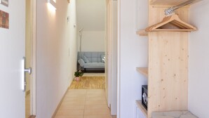 Un pasillo estrecho con suelo de madera, un banco empotrado a la derecha y una puerta a la izquierda.
