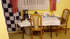 A small dining area with a table, chairs, a coffee maker, and a window with curtains. - Small apartment central location Fulda Rhön Vogelsberg Hesse 2 pers. (Künzell)
