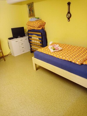 A small room with a bed, a desk with a computer, and a wall clock.