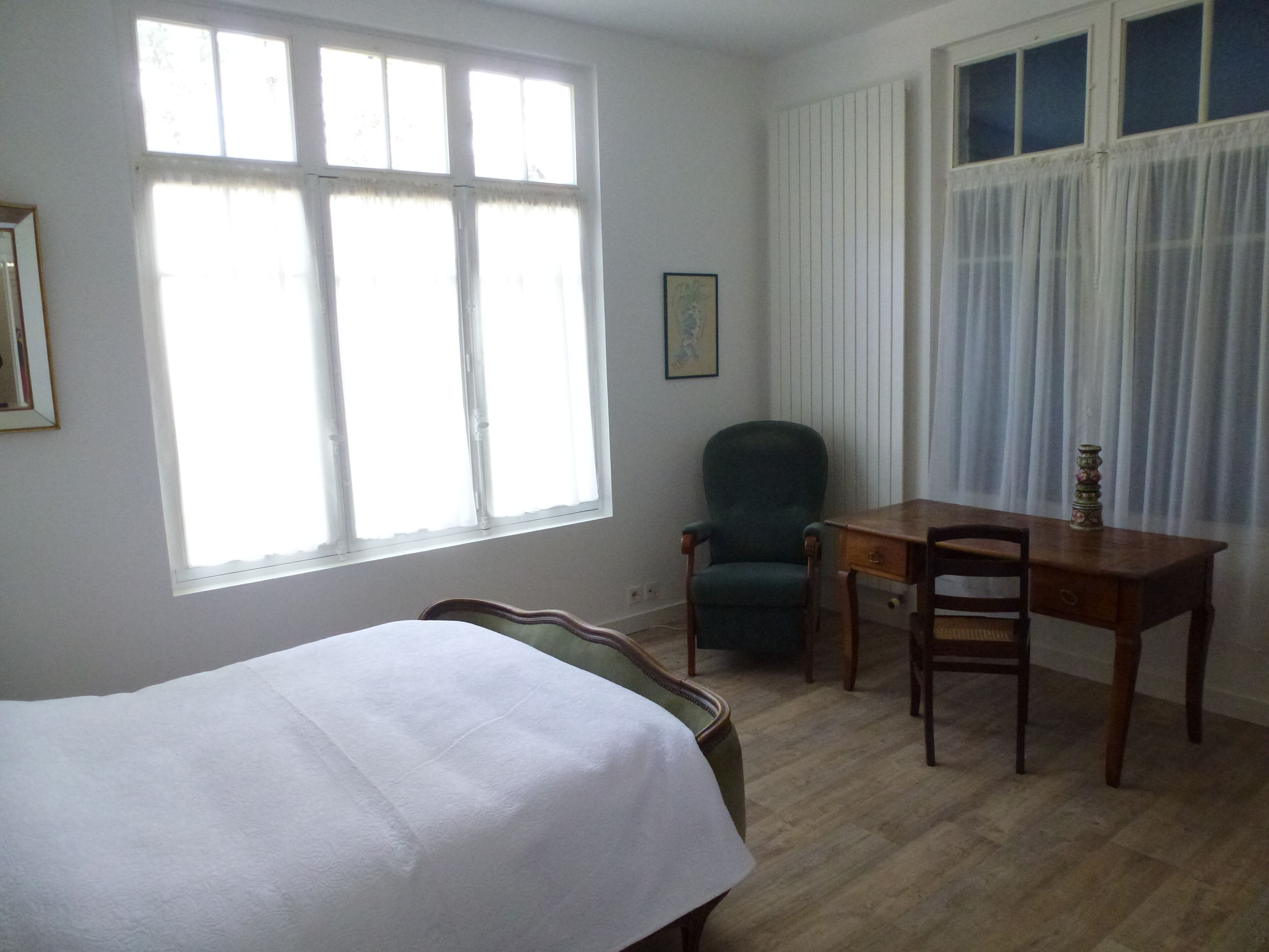 A room with a bed, a desk, a chair, and a window with curtains.