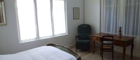 A room with a bed, a desk, a chair, and a window with curtains.