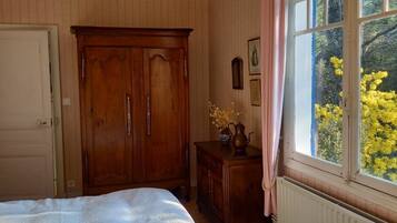 Un dormitorio con cama, armario de madera, cómoda y ventana con vistas a árboles.