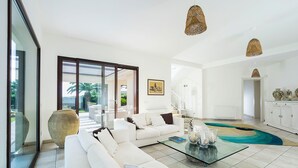 Un salon moderne avec un canapé blanc, une table basse en verre et un grand vase.