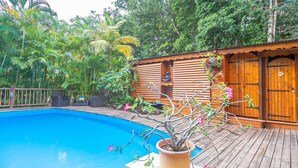 Eine Holzhütte mit Pool, umgeben von üppigem Grün.